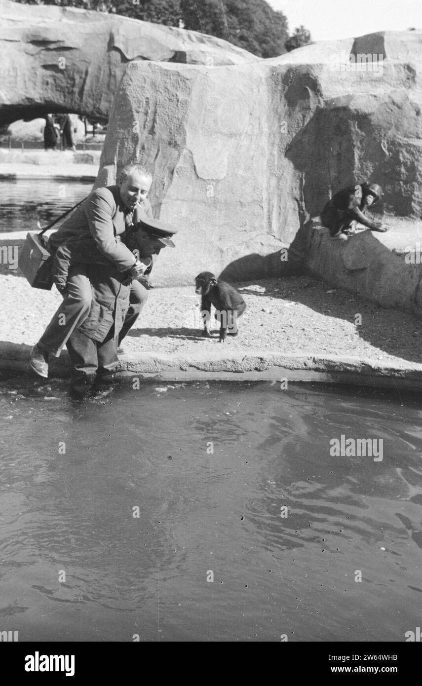 Willem van de Poll is carried by a man in uniform over the water of a monkey enclosure at Vincennes Zoo ca. 1936 Stock Photo
