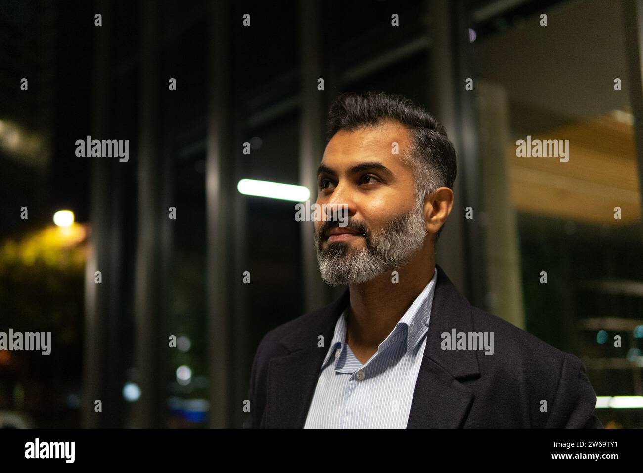 Side view of confident businessman dressed in suit and looking away while standing in workplace Stock Photo