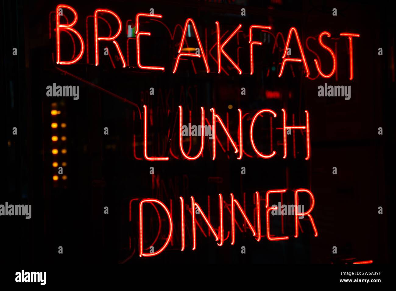 Vibrant red neon signs advertising breakfast, lunch, and dinner glow in ...