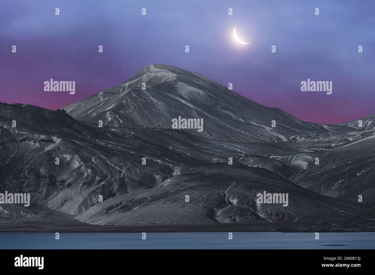 The crescent moon hangs above a serene Icelandic mountain landscape ...