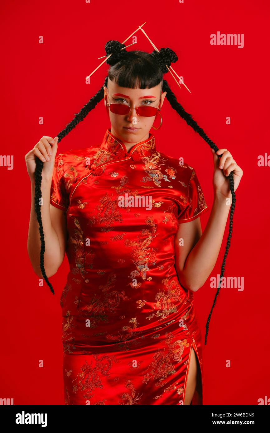 Woman in traditional red Chinese dress posing on red background with a ...