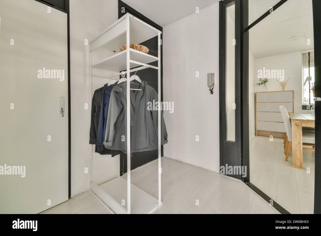 A sleek, modern entryway featuring a white open wardrobe with coats, a ...