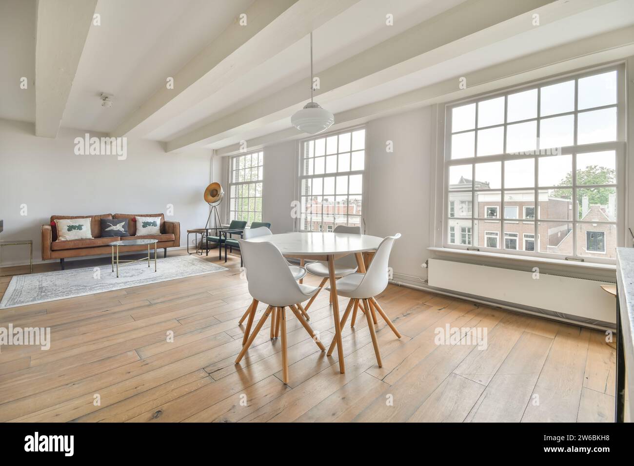 A modern living room with large windows, wooden floors, and stylish ...