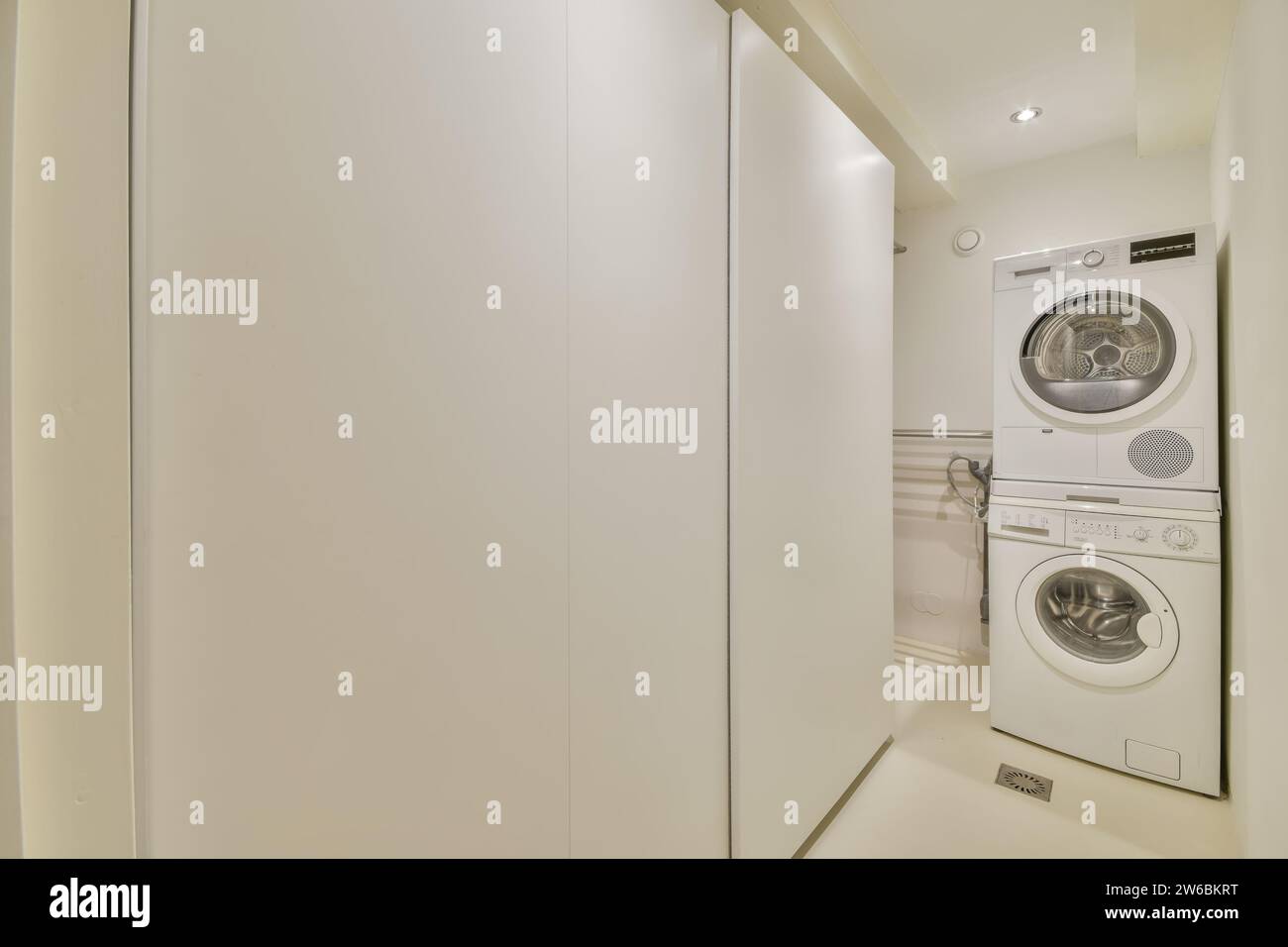 A sleek, spacesaving stacked washer and dryer set inside a narrow laundry closet with clean