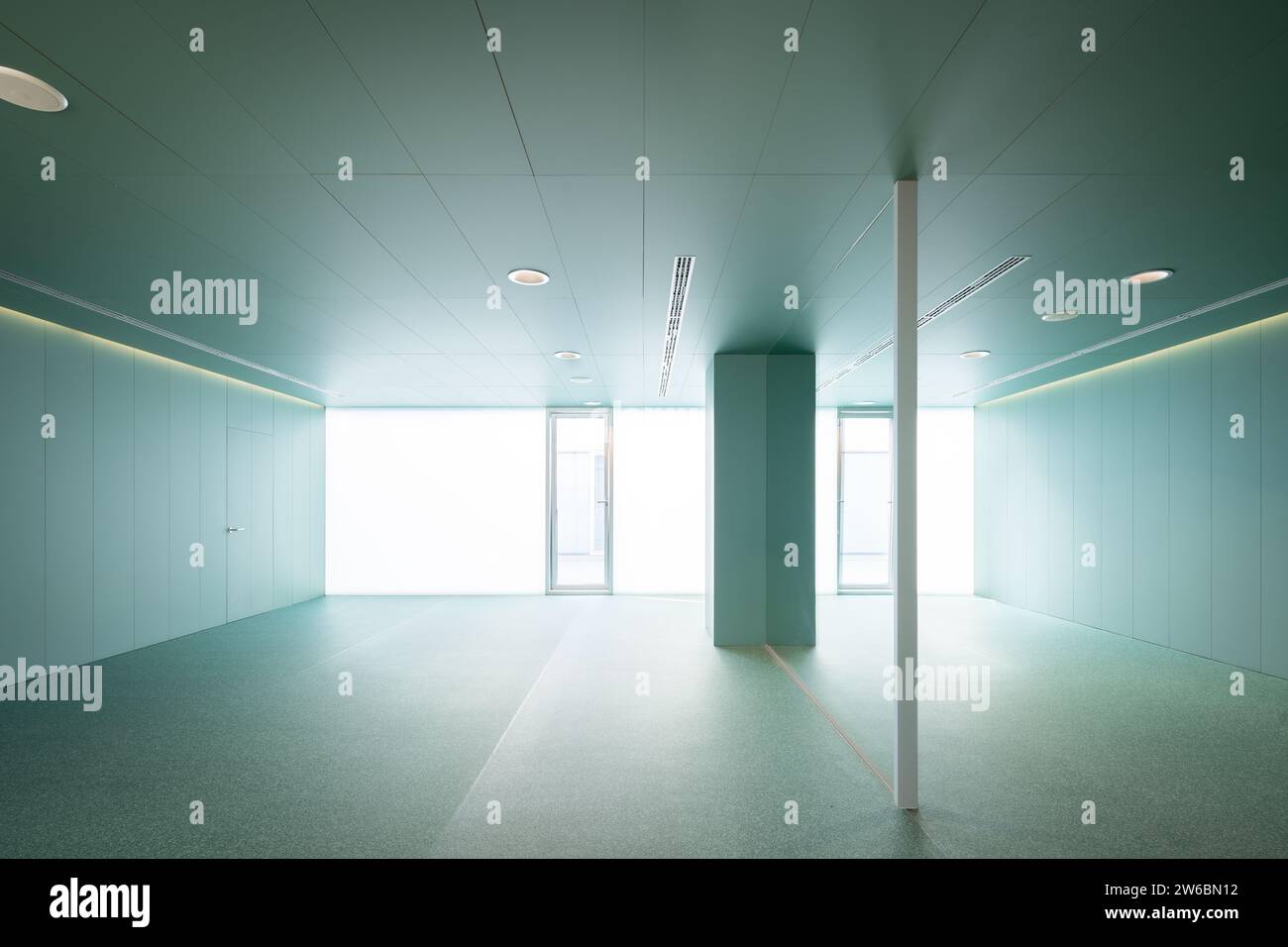 Interior of spacious empty lobby with green walls and glass partition ...