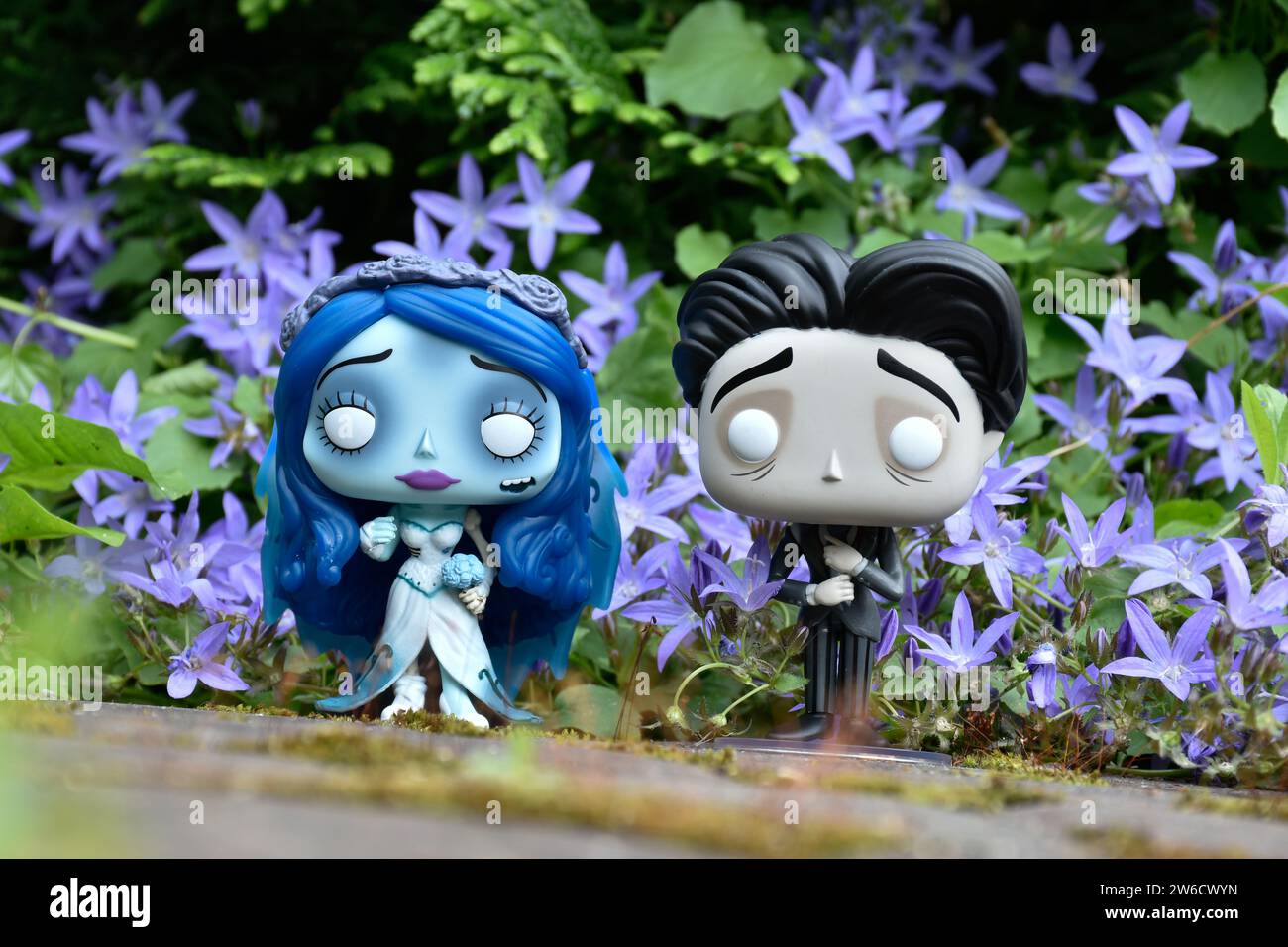 Funko Pop action figures of Emily and Victor from dark fantasy animated film Corpse Bride. Blue flowers, moss, garden, wedding, couple, romance. Stock Photo
