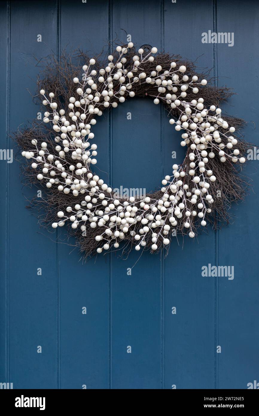 Close up of a beautiful white Christmas wreath hanging on a blue wooden door in the village of Lacock, Wiltshire, England, UK.  December Stock Photo