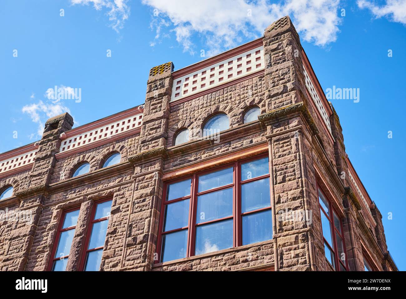 Majestic Vintage Stone Building with Arched Windows and Battlements, Low Angle Stock Photo