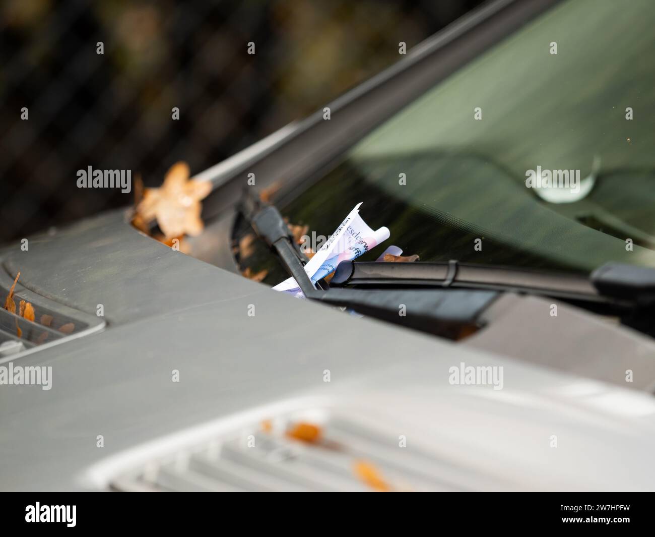 Fine for a parking offender. A ticket is behind the windscreen wiper. The car driver has to pay a penalty for violating the rules. Close up of the fee Stock Photo