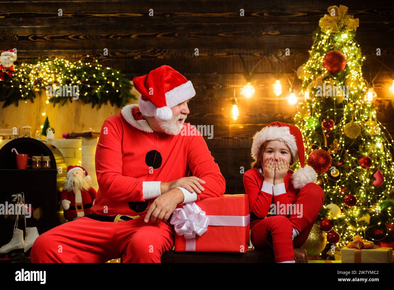 Family holidays celebration. Surprised child boy and bearded man in Santa costume with Christmas gift. New year present for kids. Santa Claus and Stock Photo