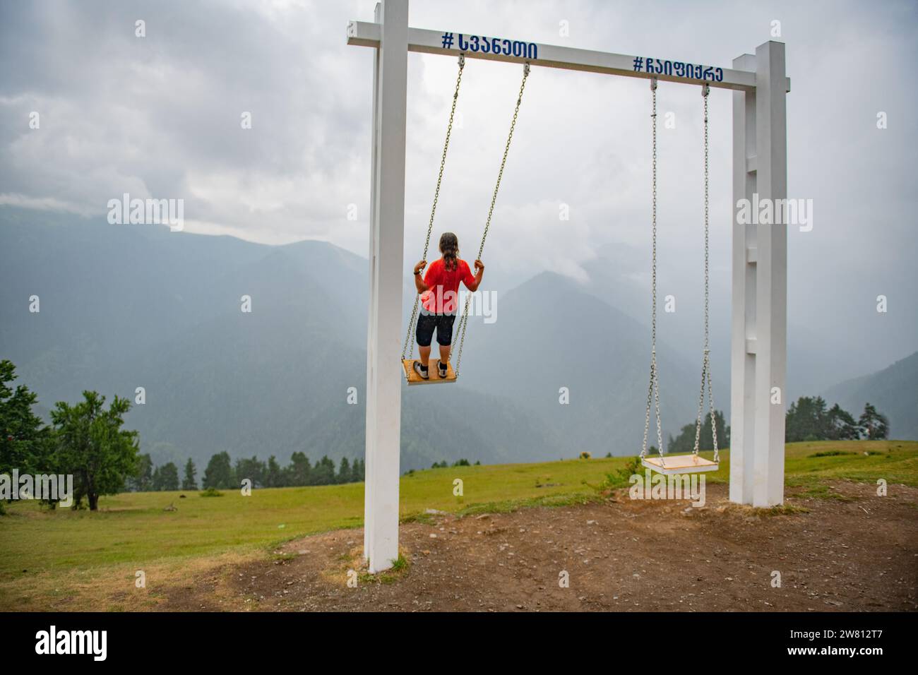 Spiraling Heights: Man Climbing High on Swing in Orange T-Shirt Stock Photo