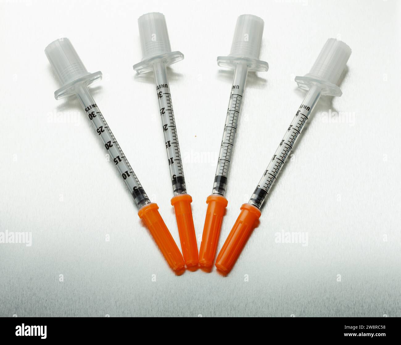 Four medical syringes with orange caps Stock Photo Alamy