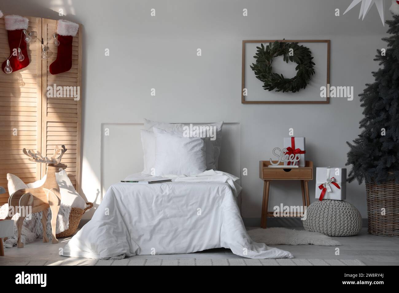 Interior of festive children's bedroom with cozy bed and Christmas decorations Stock Photo