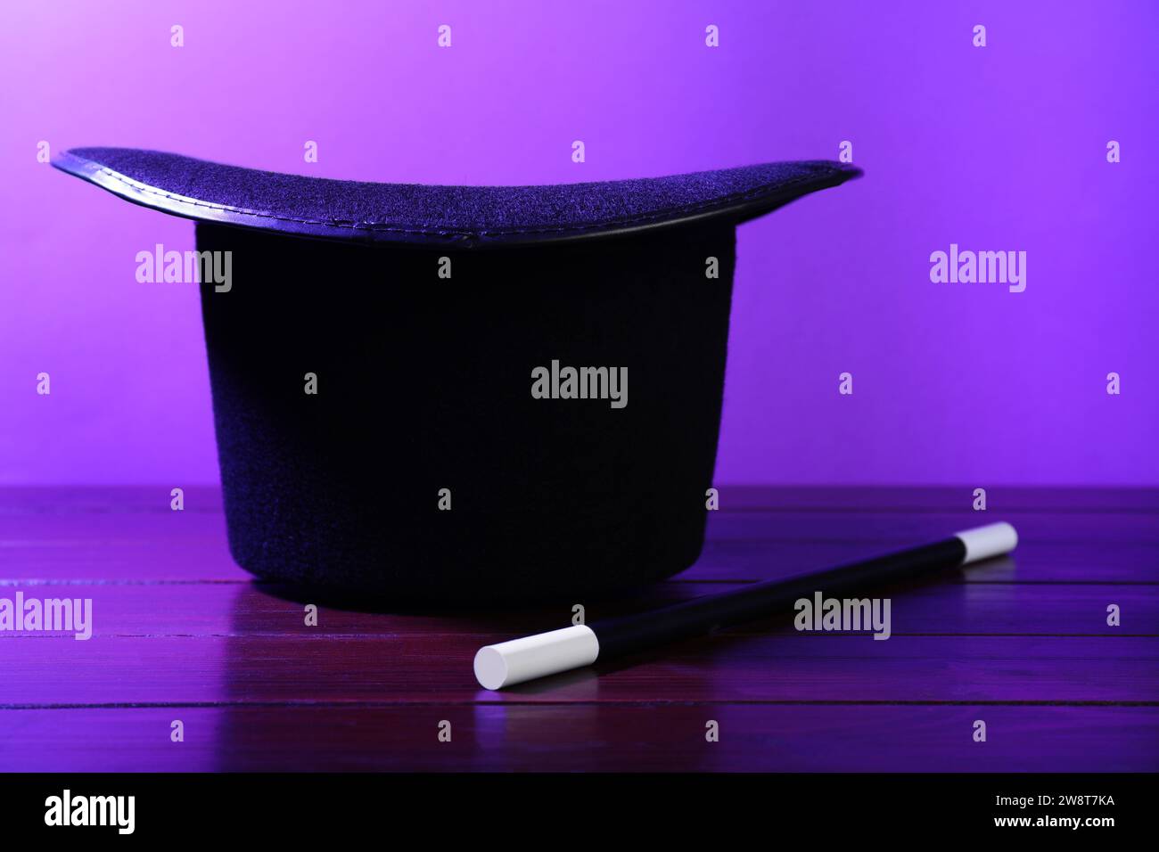 Black top hat and wand on wooden table. Magician equipment Stock Photo