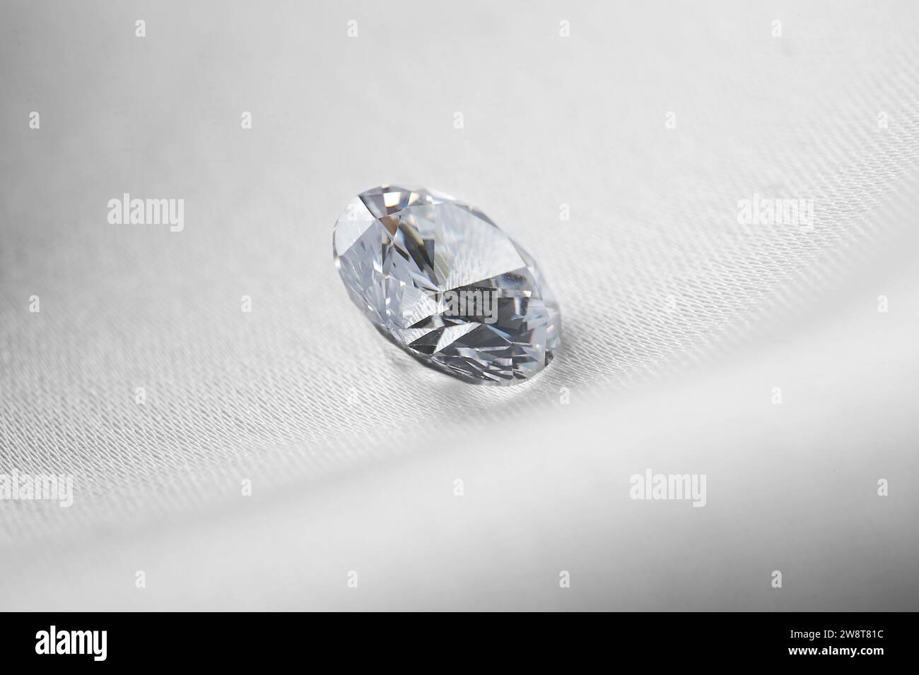 Beautiful shiny diamond on white fabric, closeup Stock Photo