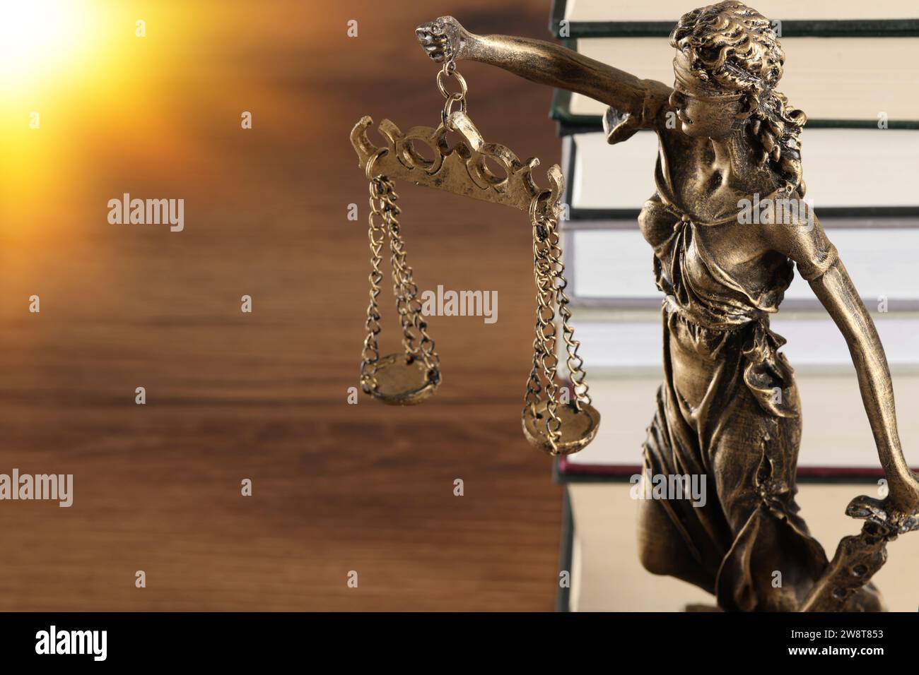 Symbol of fair treatment under law. Statue of Lady Justice and books on wooden table, space for text Stock Photo