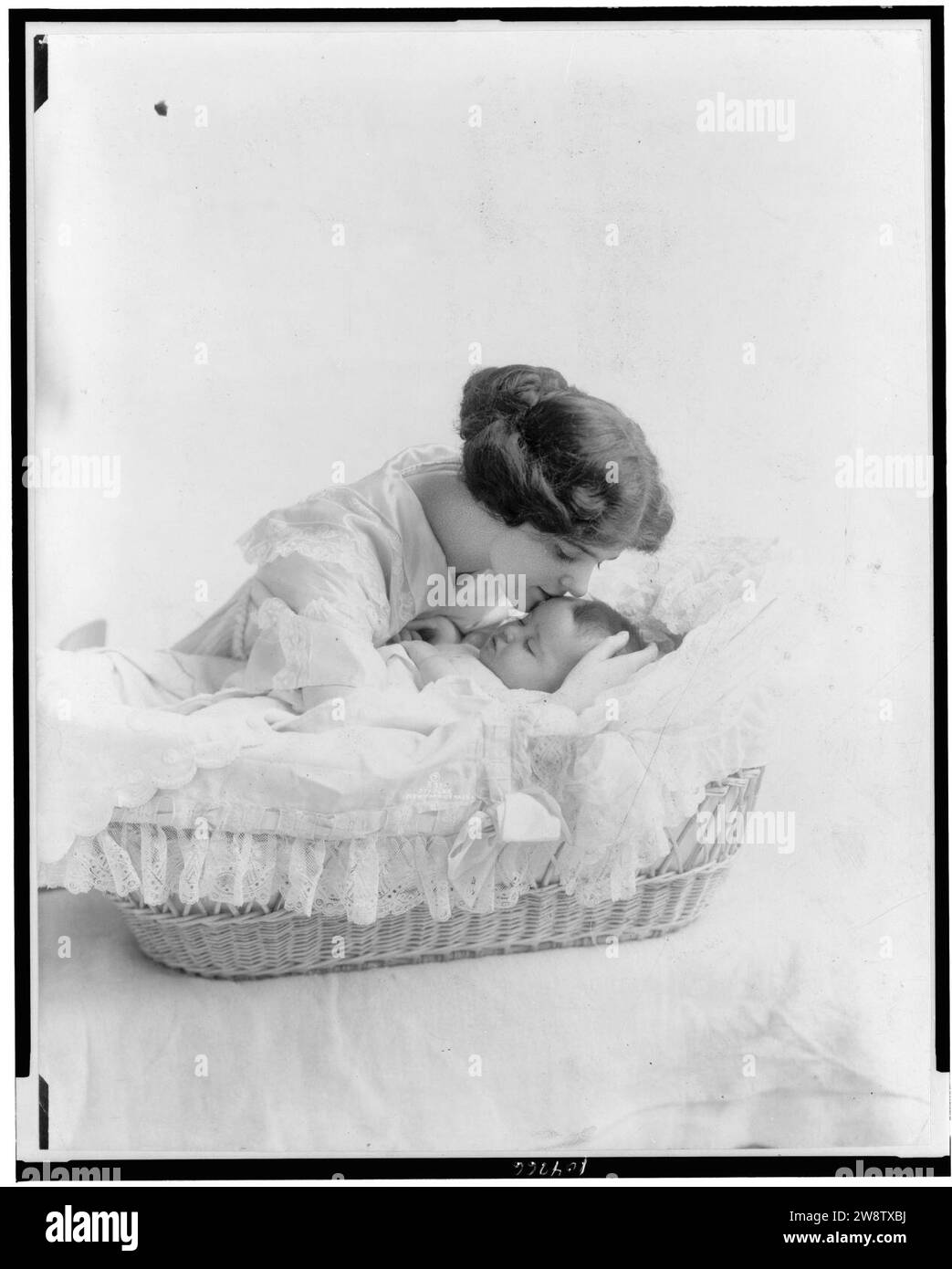 Young woman kissing baby in bassinet Stock Photo - Alamy