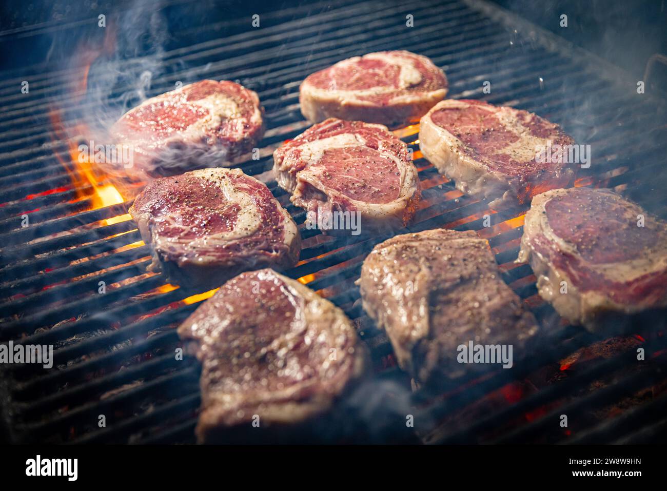 Steaks are in various stages of cooking, with some appearing more well