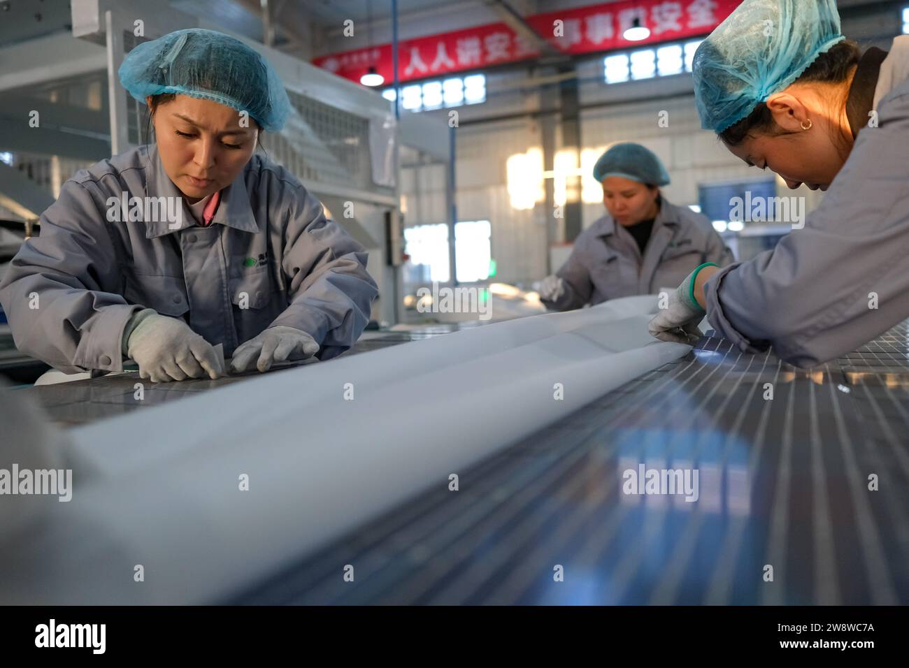 Mori, China's Xinjiang Uygur Autonomous Region. 21st Dec, 2023. Staff members work at a photovoltaic component workshop in Kazak Autonomous County of Mori, Changji Hui Autonomous Prefecture, northwest China's Xinjiang Uygur Autonomous Region, Dec. 21, 2023. With abundant solar and wind energy, Kazak Autonomous County of Mori has sped up the development of clean energy, attracting many new energy enterprises here. Credit: Zhang Cheng/Xinhua/Alamy Live News Stock Photo