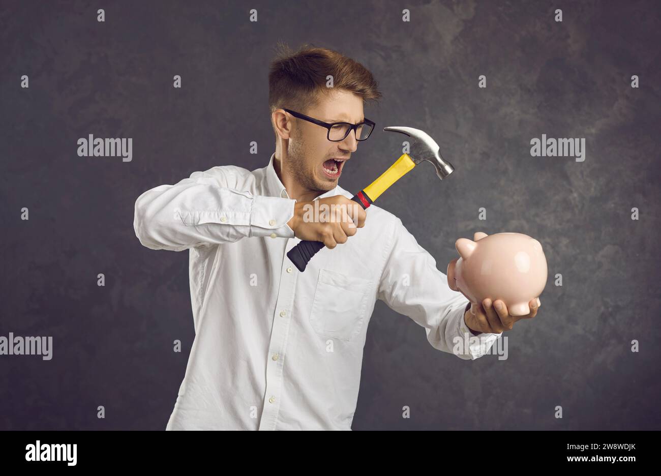 Angry man break piggybank for cash money Stock Photo