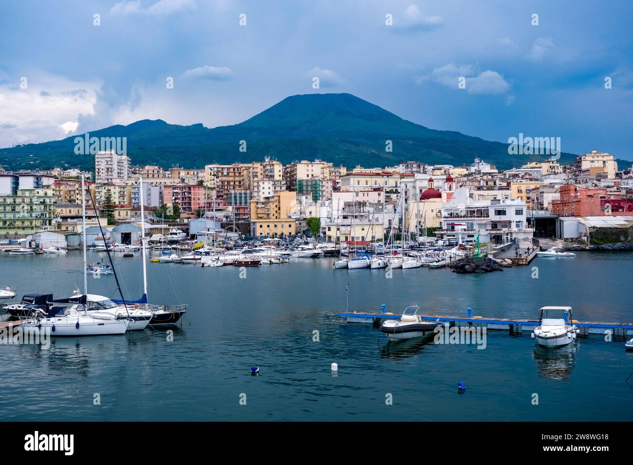 Marina and houses of the town of Torre del Greco, the volcano Vesuvius in the distance. Stock Photo