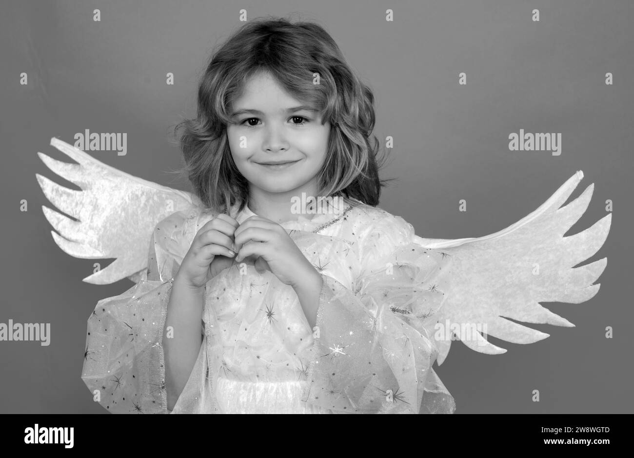 Kid wearing angel costume white dress and feather wings. Innocent child