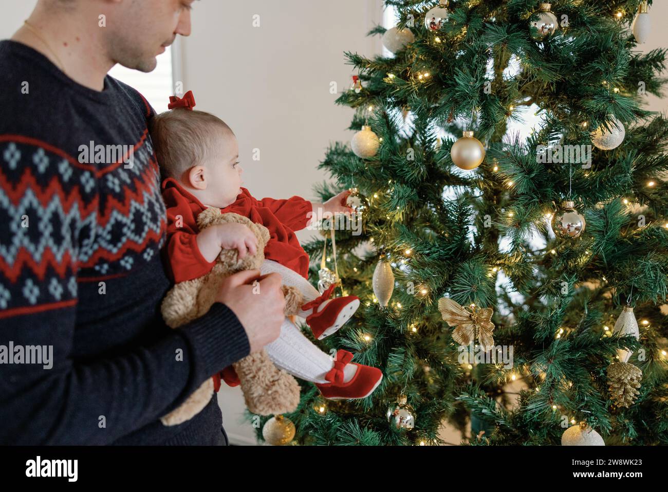 Dad and baby girl sharing christmas tree fun Stock Photo