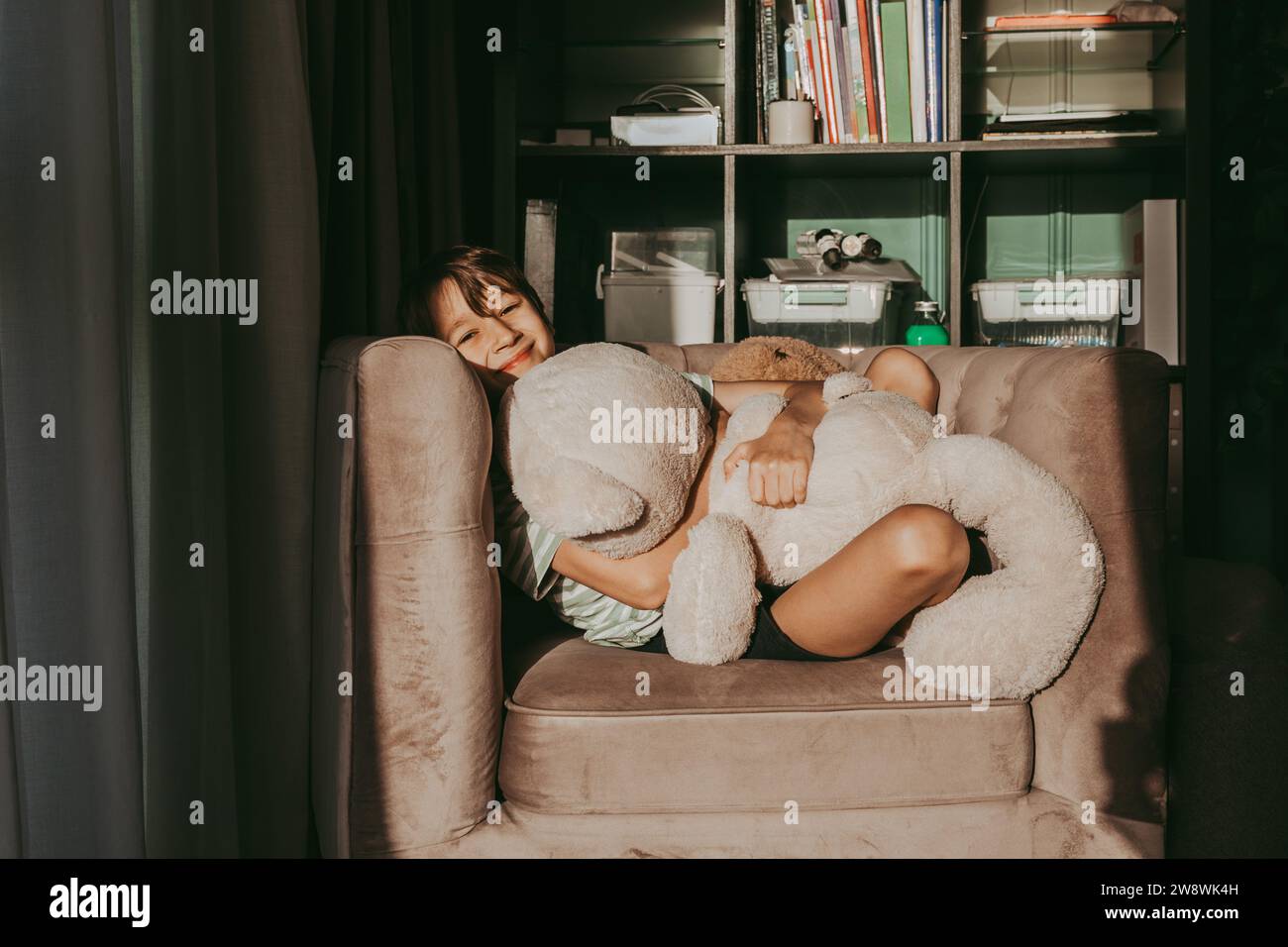 A smiling boy hugs a teddy bear in a chair Stock Photo - Alamy