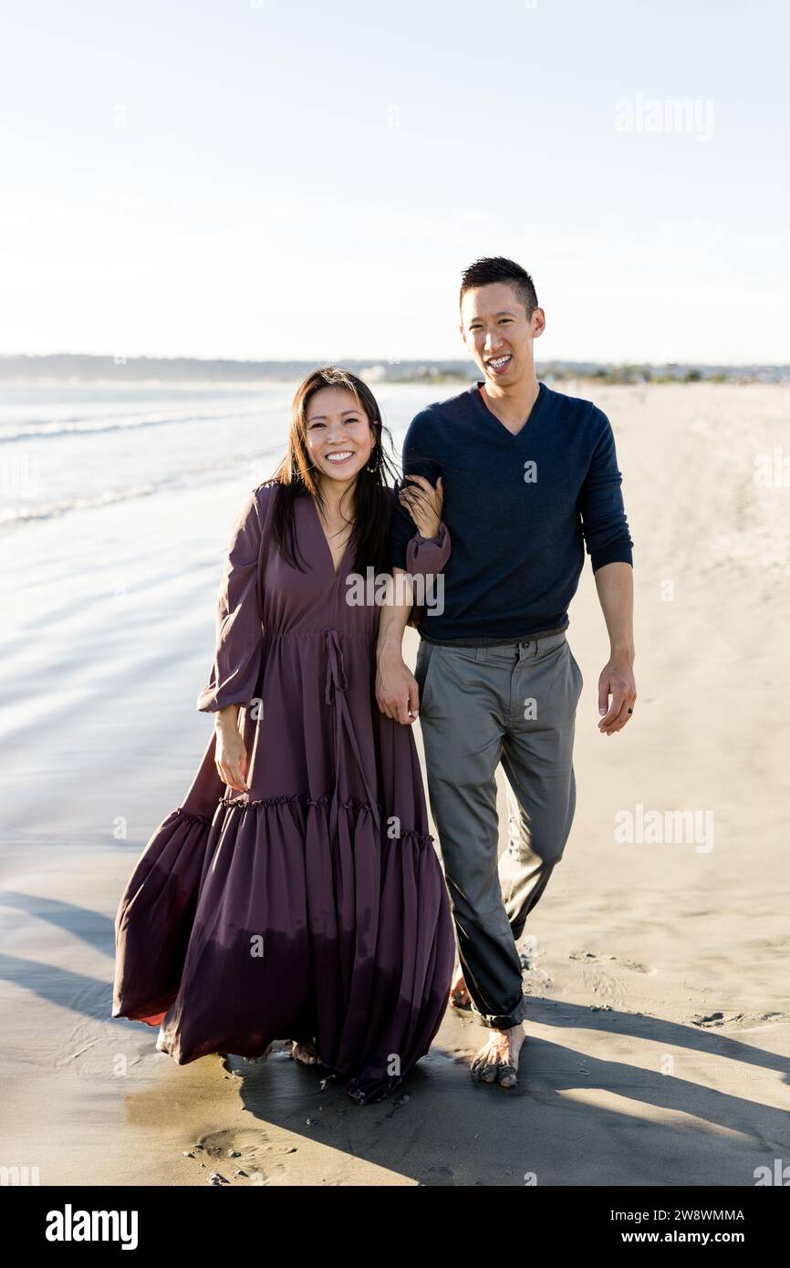 Asian Couple Walking Along Beach at Sunset in San Diego Stock Photo