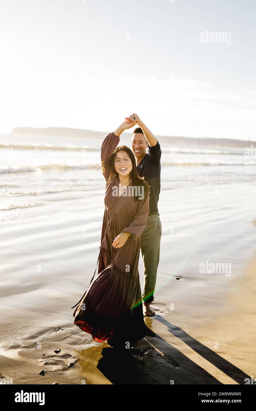 Asian Couple Dancing on Beach at Sunset in San Diego Stock Photo