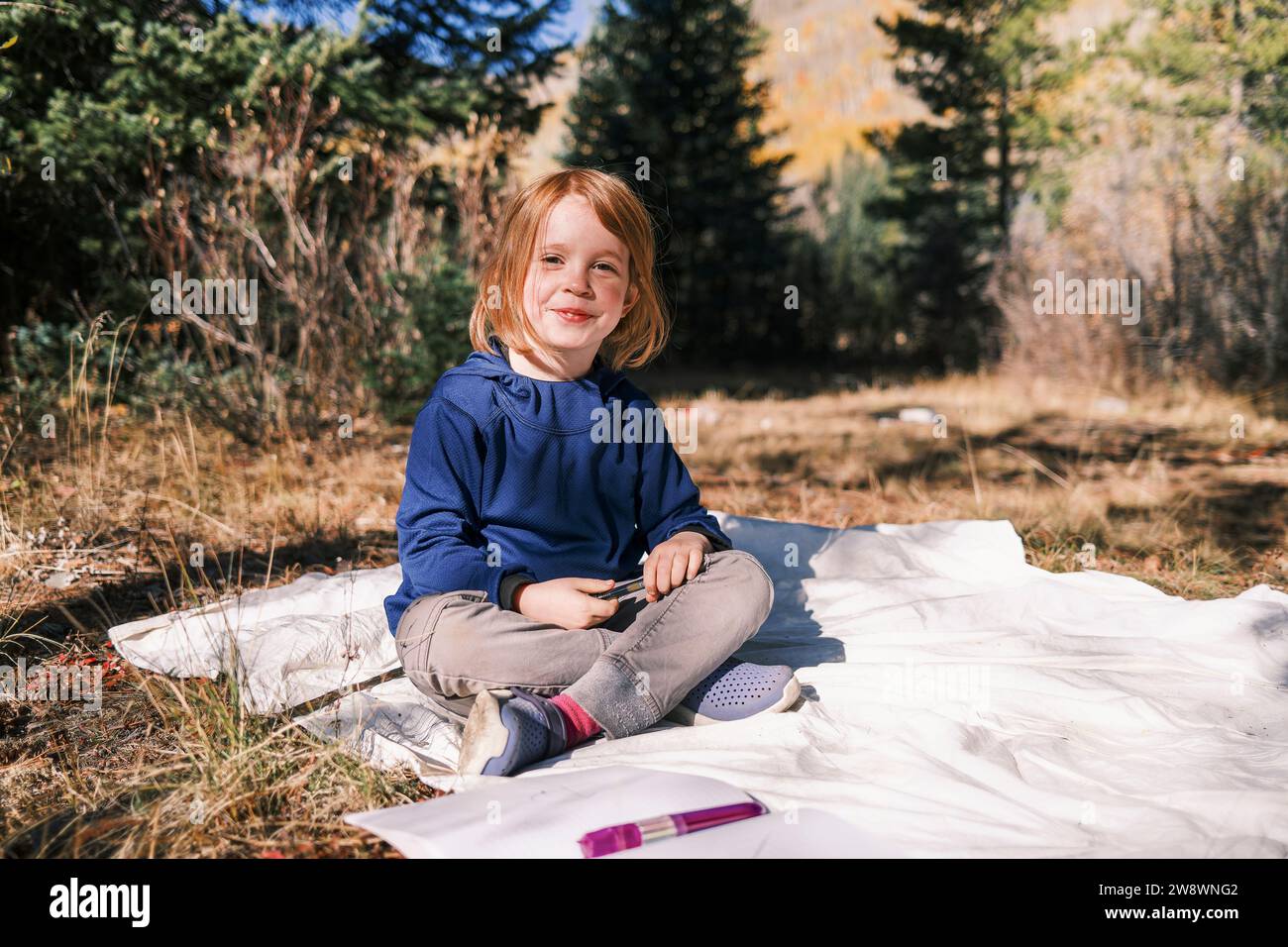 Smiling child sitting in the sun, looking at camera with happiness Stock Photo