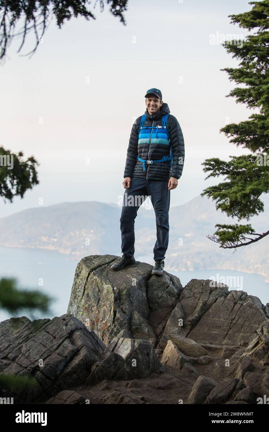 Portrait of happy hiker standing on rocky mountain summit, Stock Photo