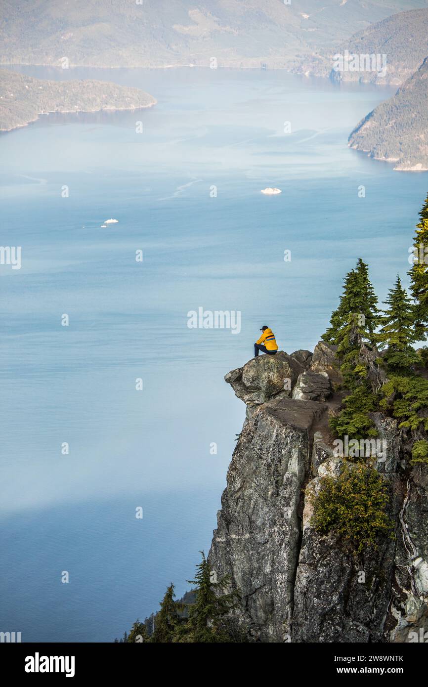 Active man sits on cliff with stunning view near Vancouver. Stock Photo