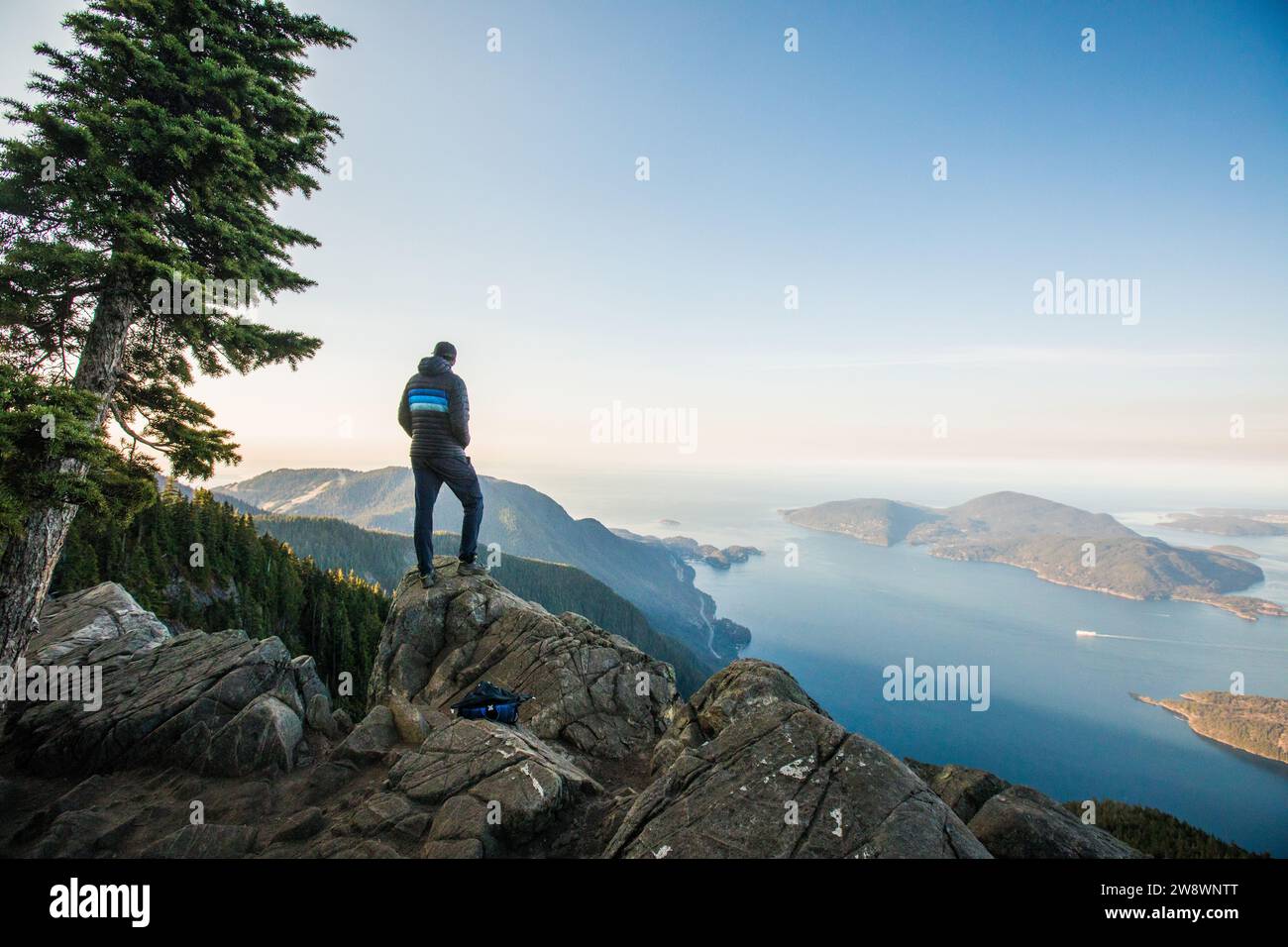 Hiker standing on summit overlooking Bowen Island, Howe Sound. Stock Photo