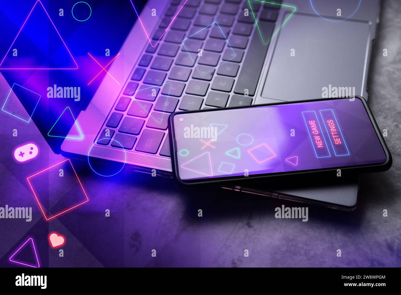 Smartphone laying on laptop with gaming interface on screen. Playing online concept with empty space for text. Online entertainment and gamification. Stock Photo