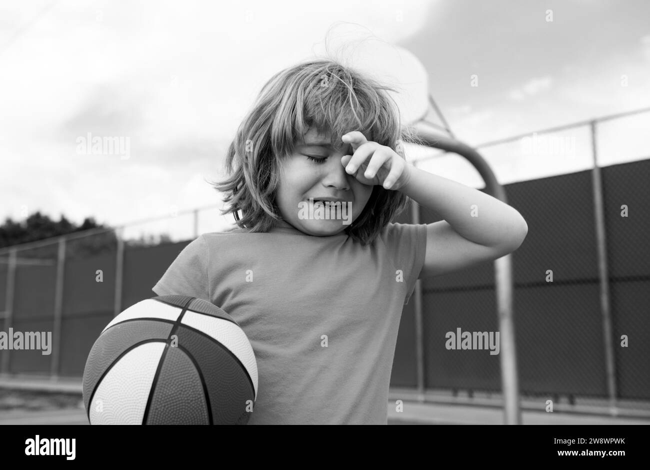 Boy cries of resentment and grief. Little boy alone, lonely with ball. Loneliness kids. Sad child boy portrait. Stock Photo