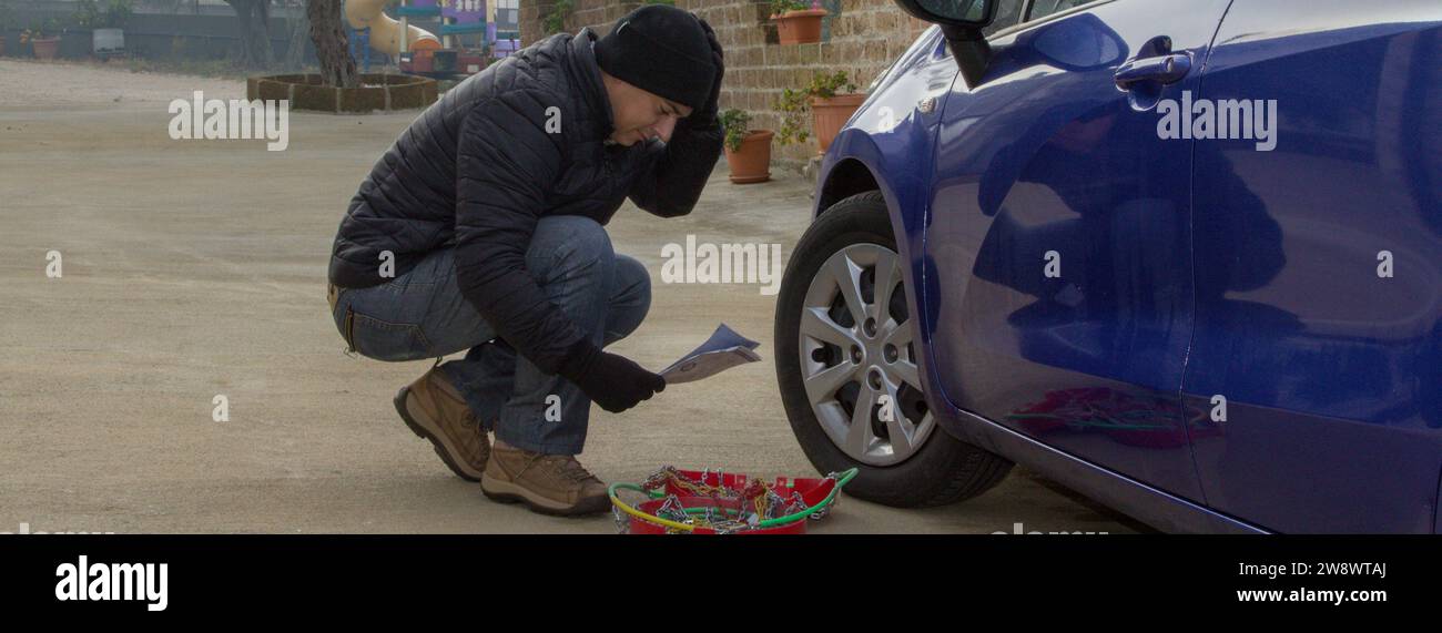 Image of a man trying to fit snow chains to his car Stock Photo Alamy