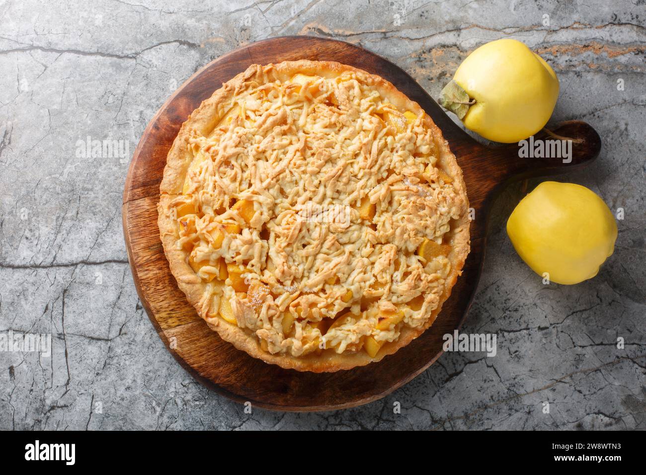 Delicious autumn quince pie with streusel closeup on the wooden board on the table. Horizontal top view from above Stock Photo