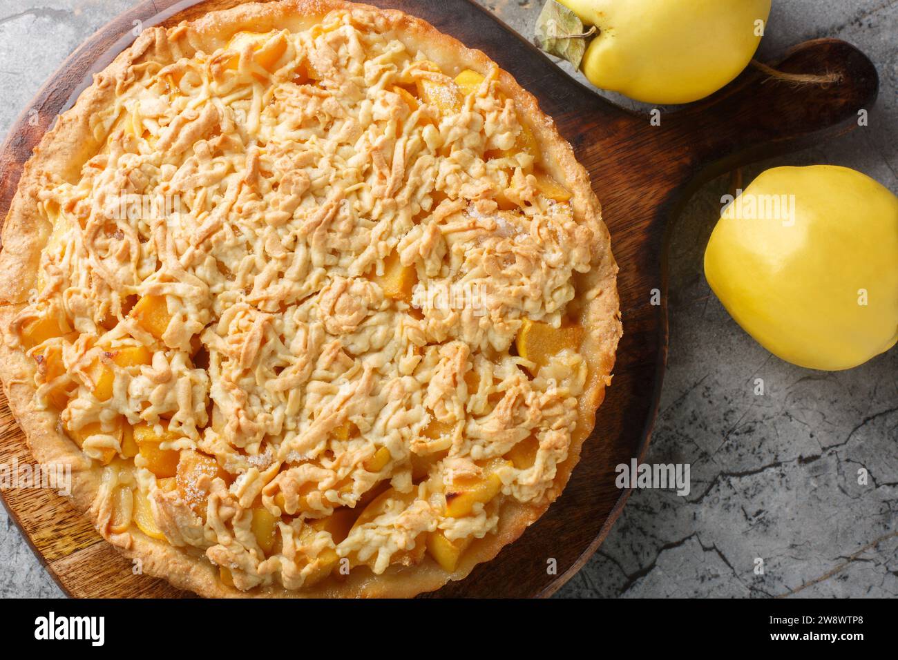 Autumn fragrant crust quince pie tart close-up on a wooden board on the table. Horizontal top view from above Stock Photo