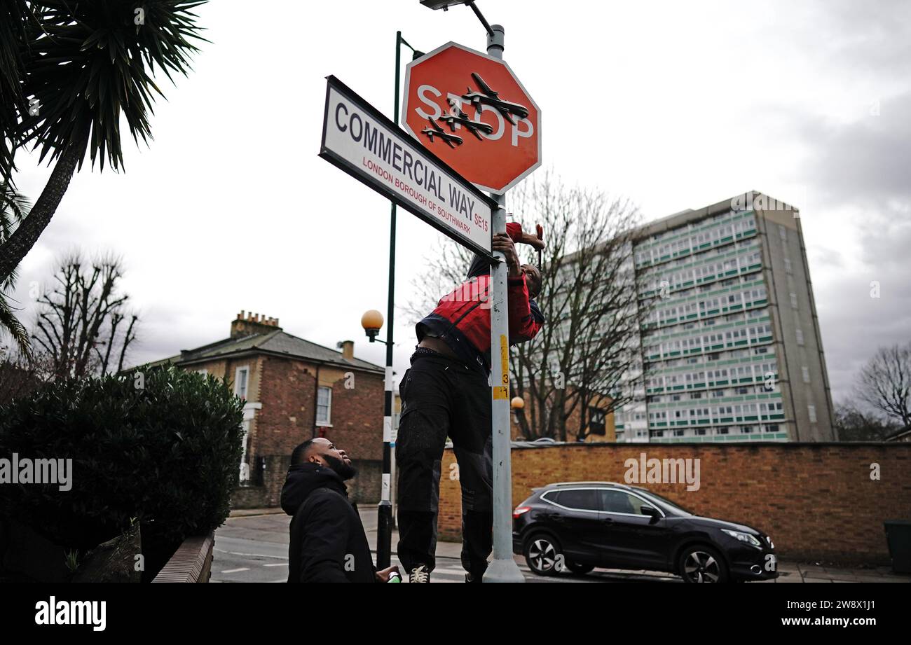 People remove a piece of art work by Banksy, which shows what looks