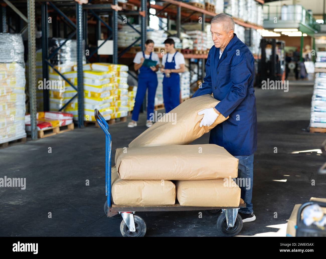 Elderly man loader with cargo cart loaded with bags Stock Photo