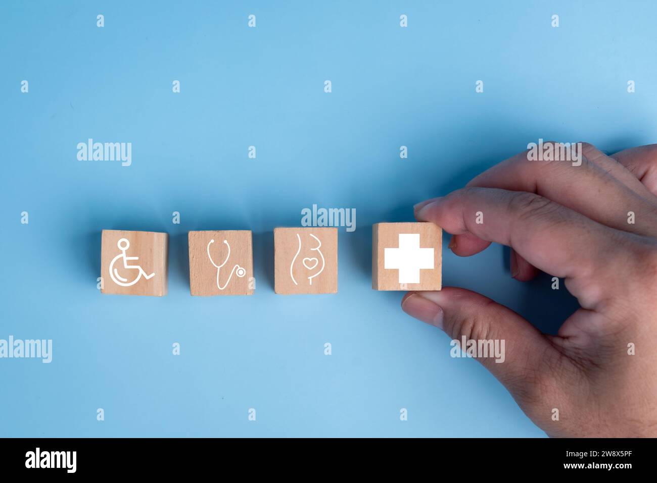 Arranging wooden block cubes into the shape of a healthcare medical icon, symbolizing insurance for your health and Plus Sign Concept. Stock Photo