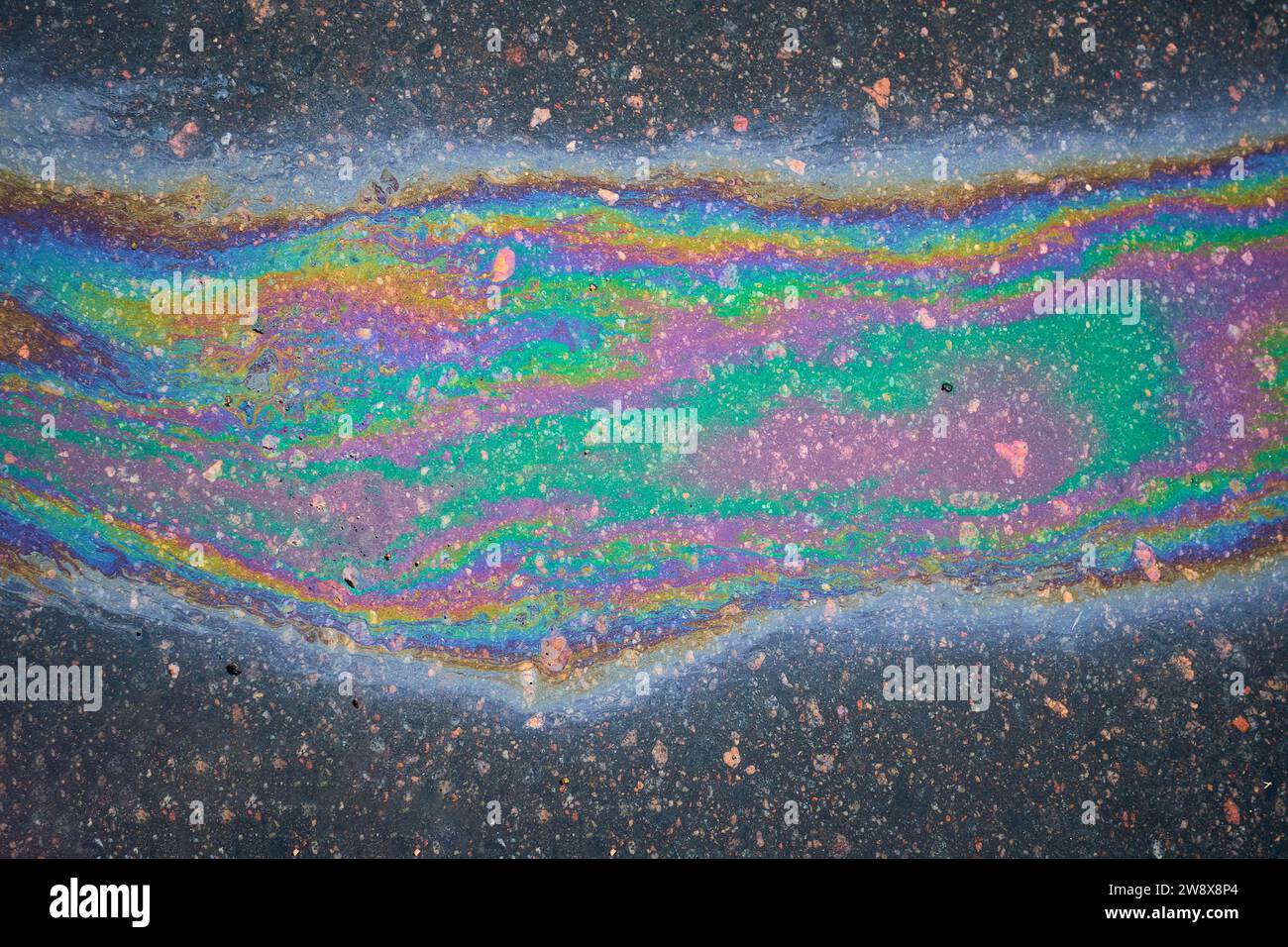 Multicolored poisonous spots of spilled gasoline on wet pavement