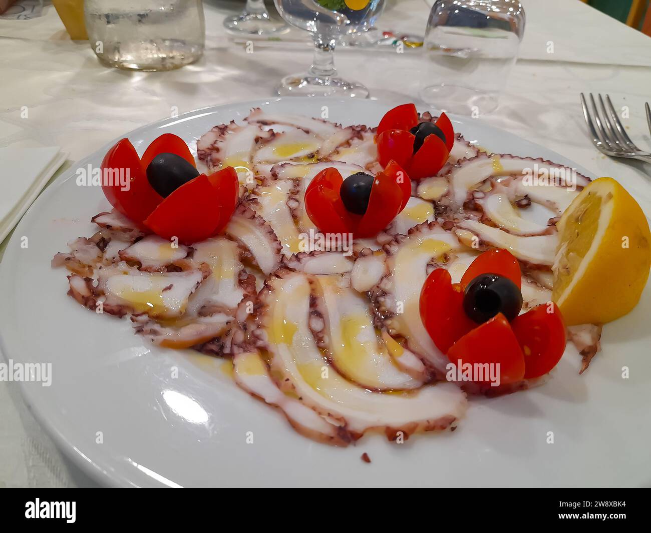 Italian-style octopus carpaccio involves thin slices of cooked octopus with red tomato Stock Photo
