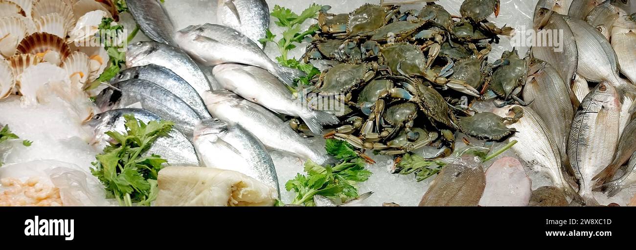 lots of fish and even fresh blue crabs on the counter full of ice for sale in the fishmongers Stock Photo