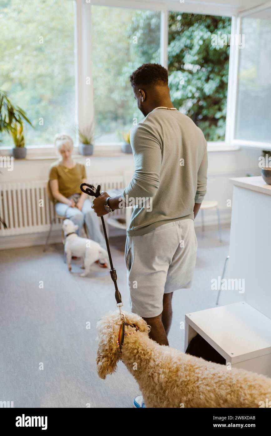 Young man walking with dog in waiting room of vet medical clinic Stock Photo