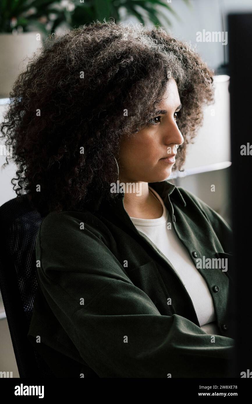 Focused businesswoman with curly hair working at office Stock Photo
