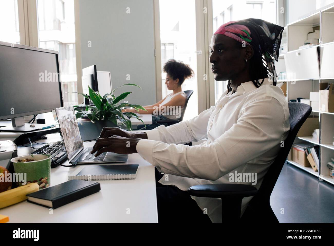 Male computer programmer using laptop while sitting on chair with ...