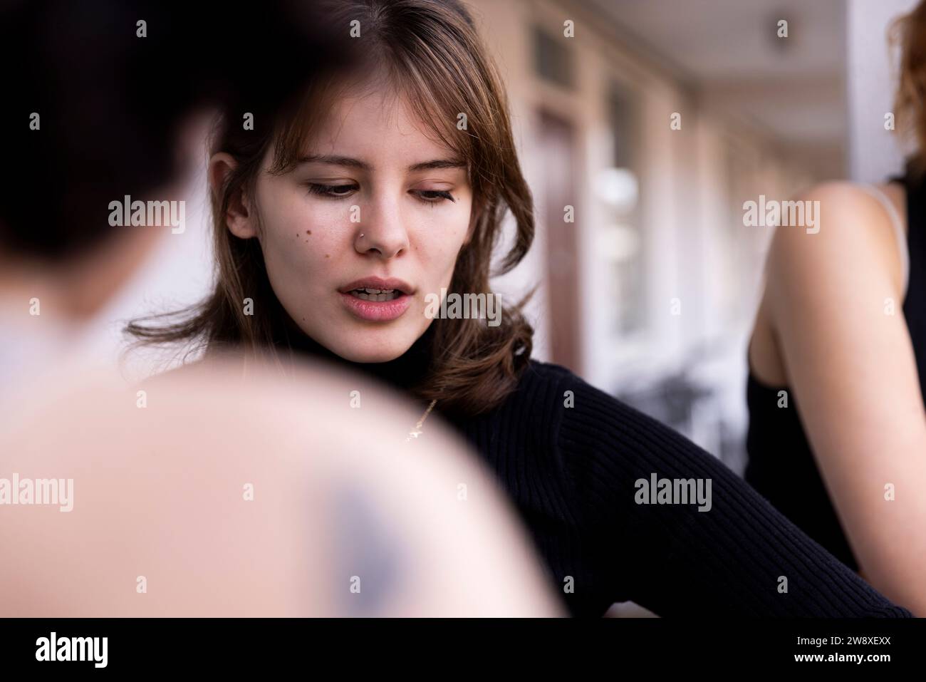 Young woman looking down with friend in balcony Stock Photo