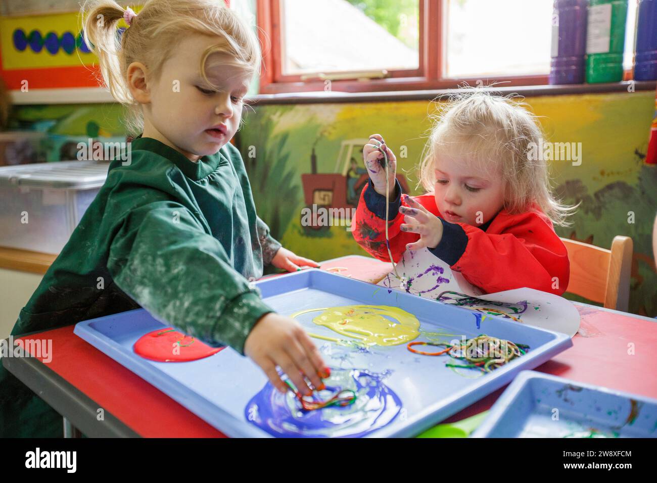 Two girls painting at a nursery school in the UK Stock Photo